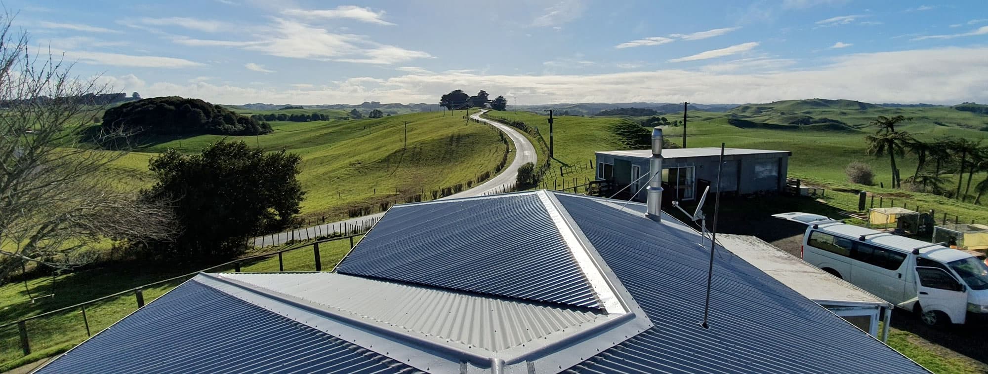 New corrugated iron roof on a rural home with green hills behind