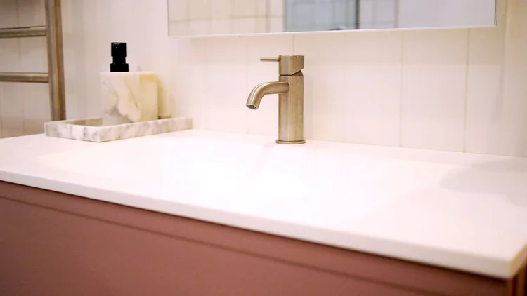 Close-up of a new vanity and brushed brass tap in a renovated bathroom